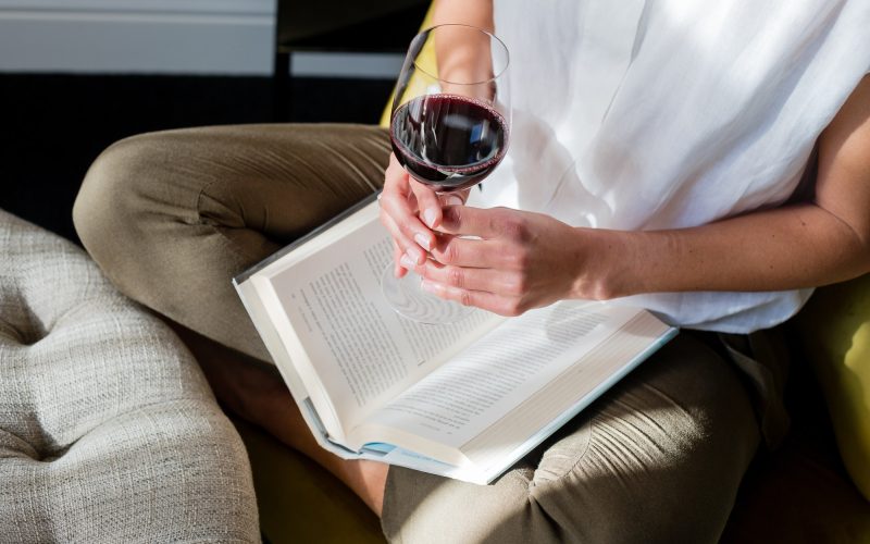 Mujer leyendo con una copa de vino